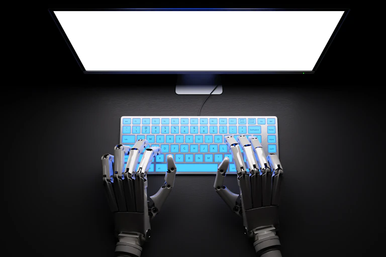 Robotic hands at a computer.