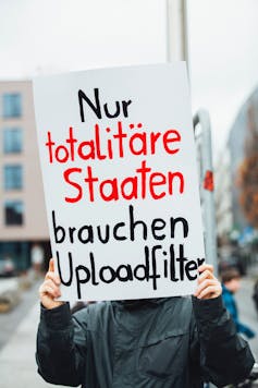 A man holds a sign in German