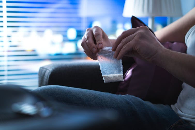 Person at home holding small bag containing white powder