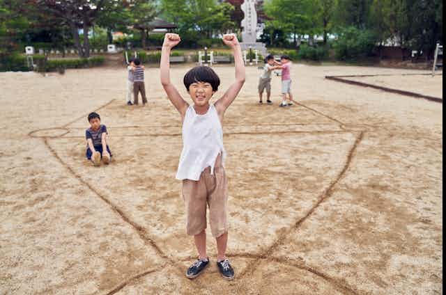 Production image: a child stands in celebration