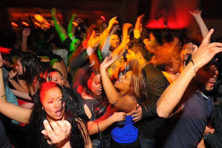 A group of people dance, arms in the air.