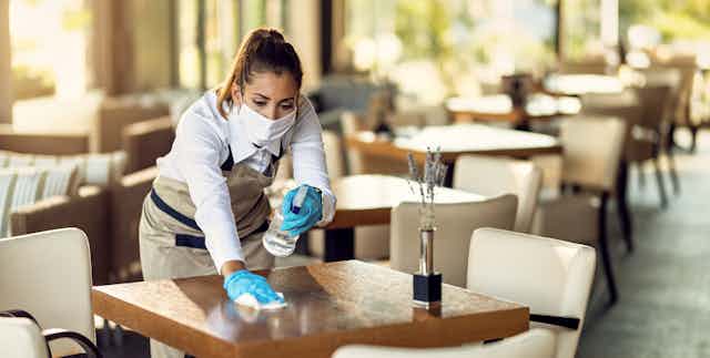 waitress disinfecting dining table