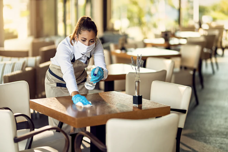 waitress disinfecting dining table