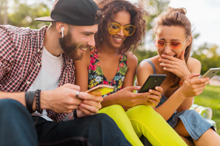 Dans un groupe de jeunes, un garçon a ses écouteurs tout en discutant avec ses amies.