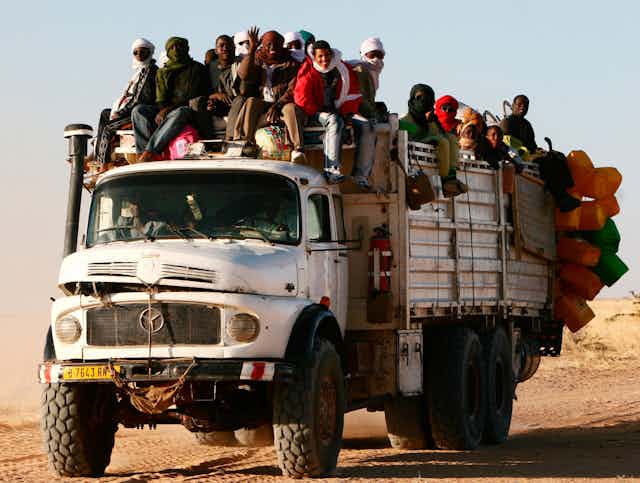 Old truck loaded with people and supplies.