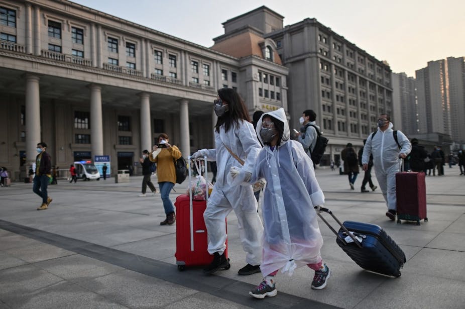 Mère et fille avec valise quittant la ville en tenue de protection bactériologique.