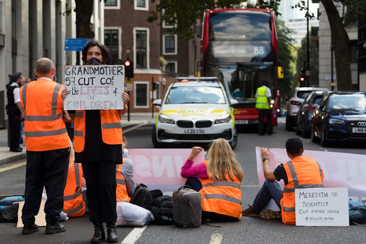 People with signs sit in a road