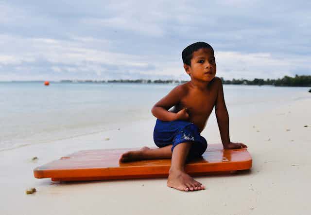 boy sits on board at beach