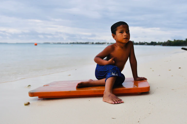 boy sits on board at beach