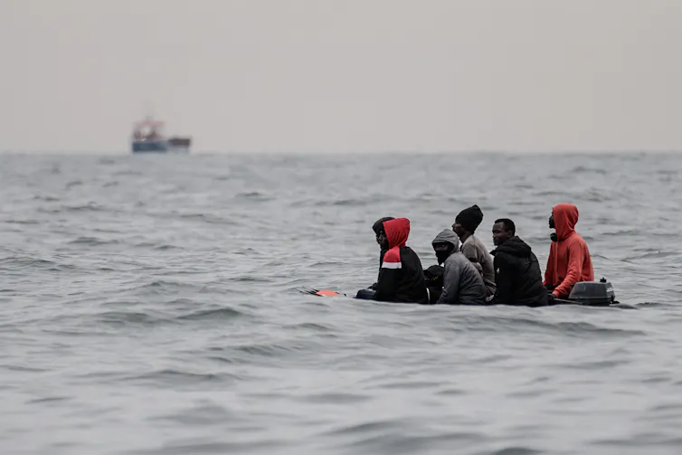 Des migrants sont assis à bord d’un bateau naviguant dans des eaux agitées entre Sangatte et le Cap Blanc-Nez, dans la Manche, au large des côtes du nord de la France, alors qu’ils tentent de franchir les frontières maritimes entre la France et le Royaume