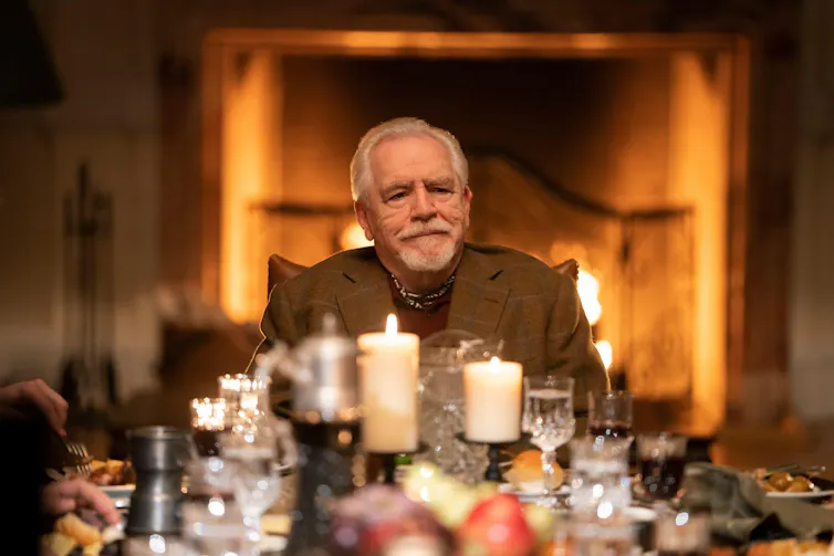 Man sits at top of table with candles