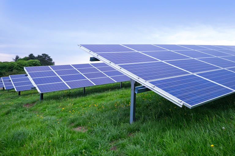 Rows of solar panel arrays on a green field.