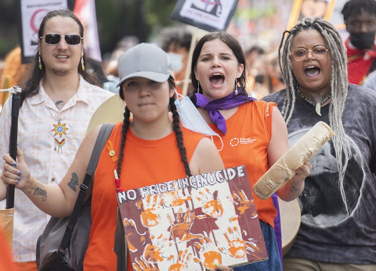 A woman holds a sign that reads 'no pride in genocide'