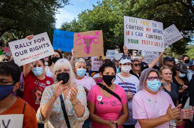 Hundreds of marchers, waving protest signs at the State Capitol building in Austin, urge Texans to oppose the state's new abortion law.