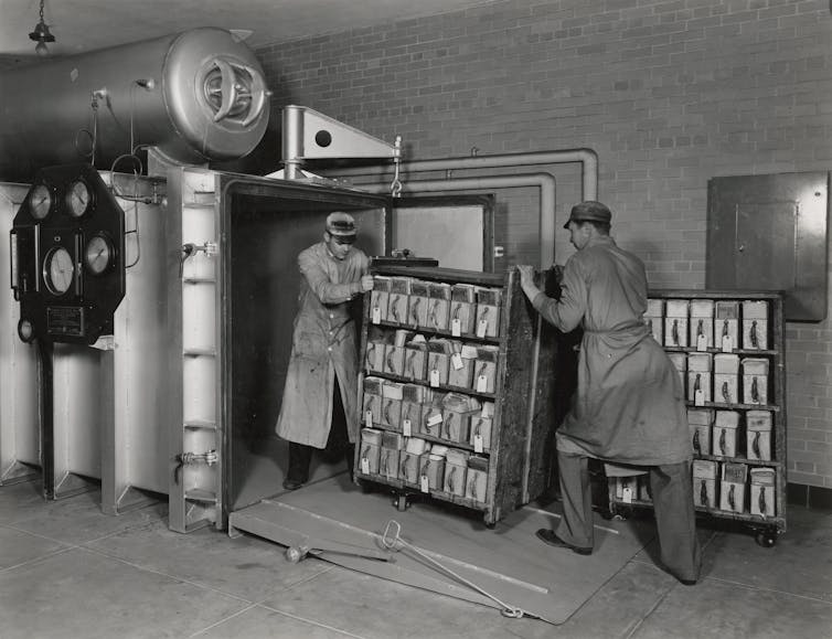 National Archives workers push a cart of Veterans Administration records into a vacuum chamber for fumigation in June 1936.