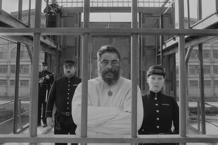 Man in a straight jacket flanked by guards.