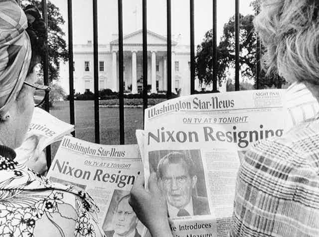 Tourists in front of the White House read headlines saying President Nixon will resign..