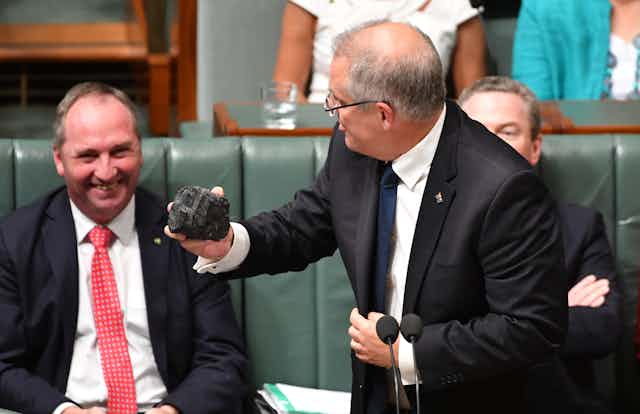 man holds lump of coal as other man smiles