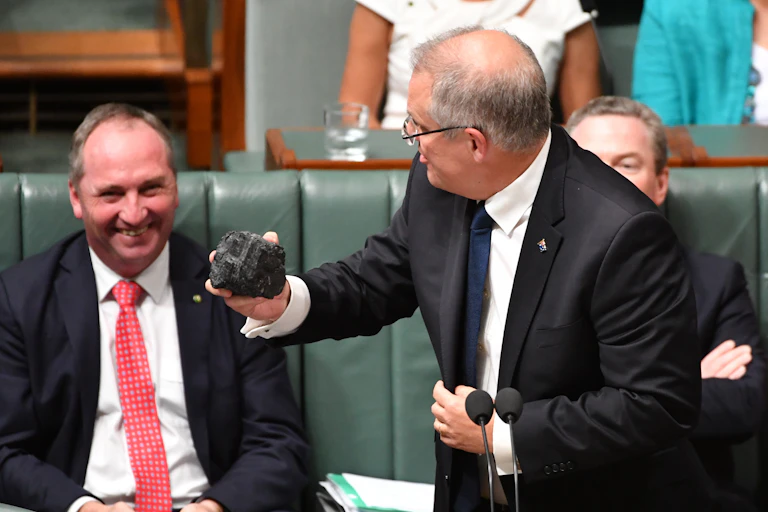 man holds lump of coal as other man smiles