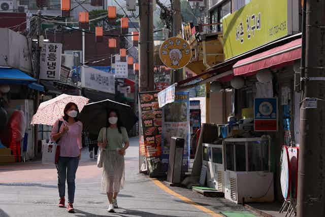 Two South Korean women wearing masks walking down a street