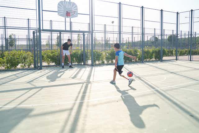 A coach plays football with a disabled child