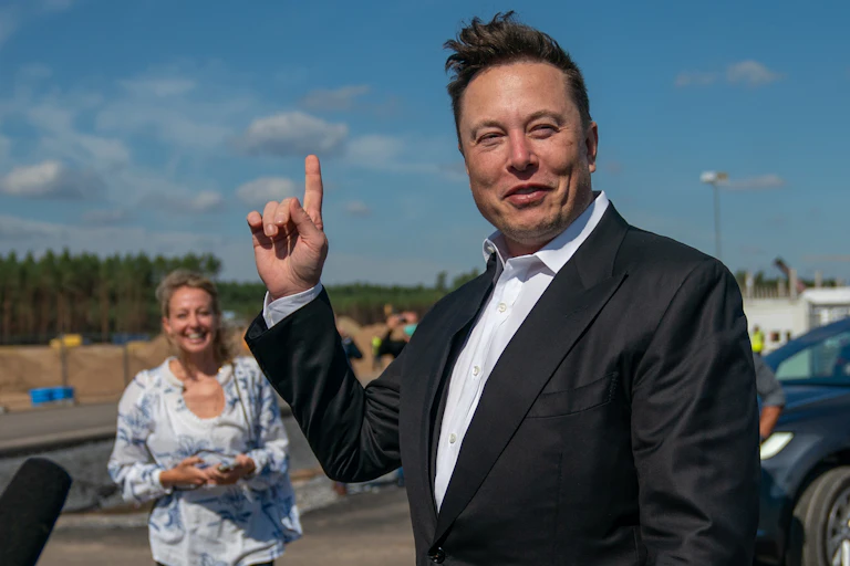 Image of Elon Musk pointing up towards the sky.