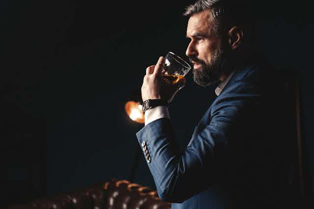A man drinking a glass of brandy