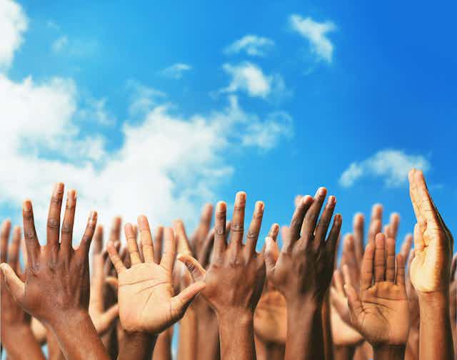 Many hands reaching up towards the sky