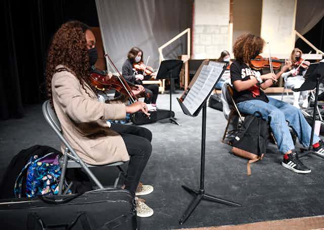 High schools students play violins while socially distanced and wearing face masks