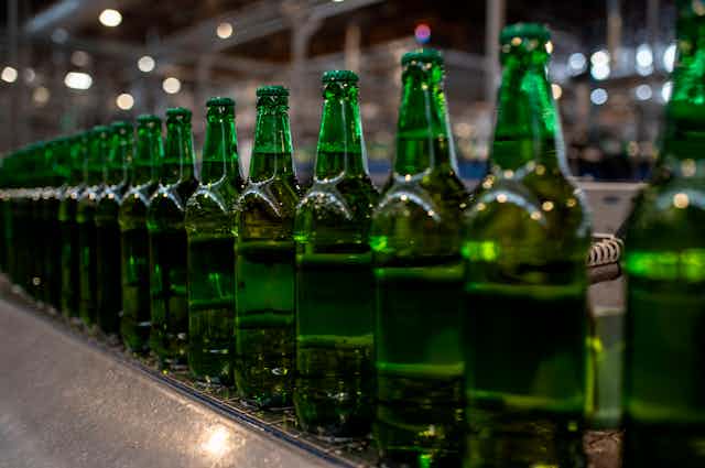 Green beer bottles lined up in a factory.
