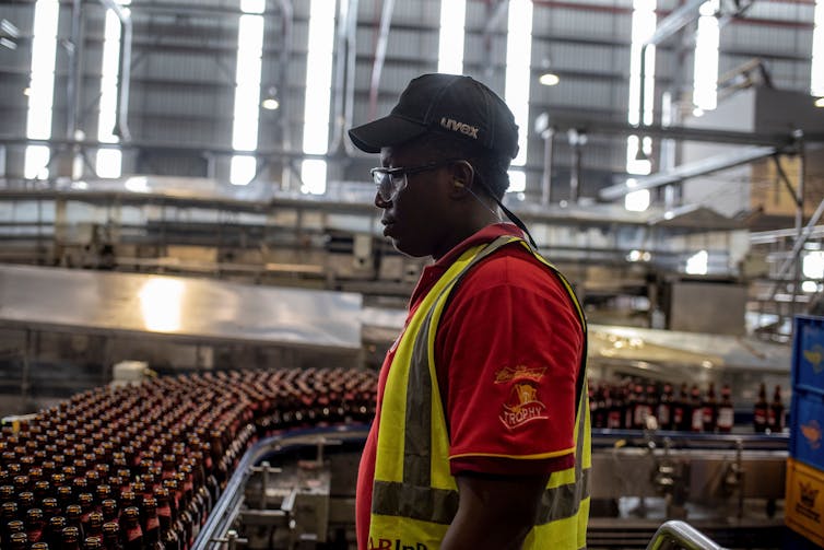 A man wearing a hat and reflector jackets in a large warehouse.