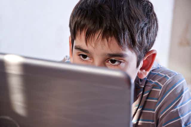 Young boy staring at a laptop screen