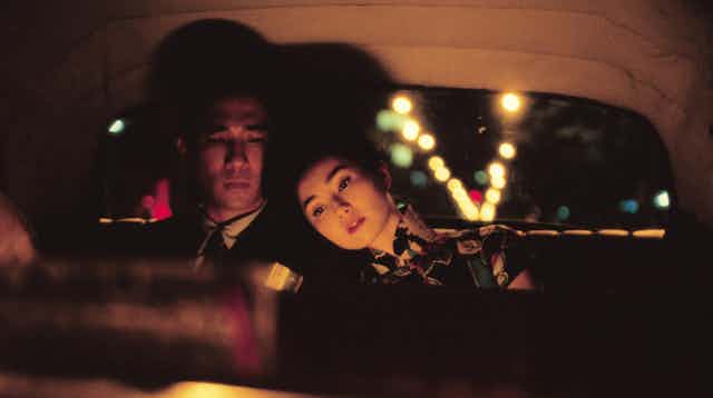 Film still: a man and a woman in the back seat of a car