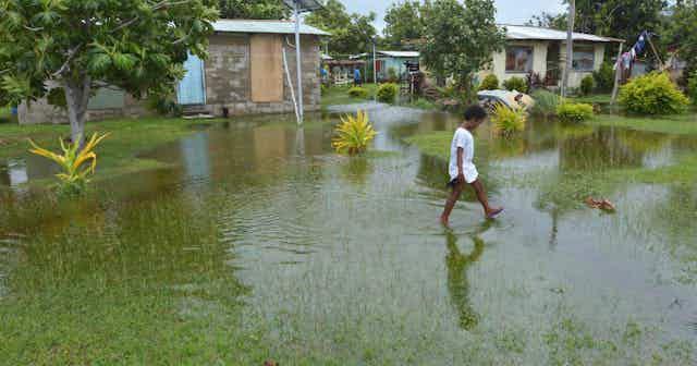 A boy walks through a flooded field in Fiji.