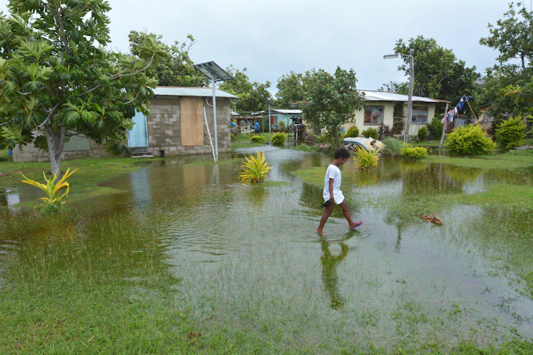 A boy walks through a flooded field in Fiji.