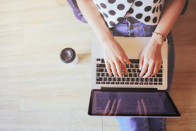 A birds-eye view of a woman sitting on the floor using a laptop.