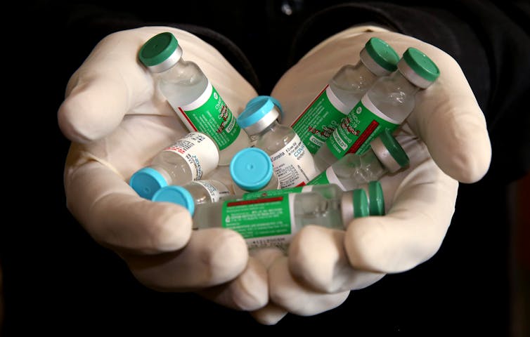 A person holding vials of the Covishield and Covaxin vaccines.