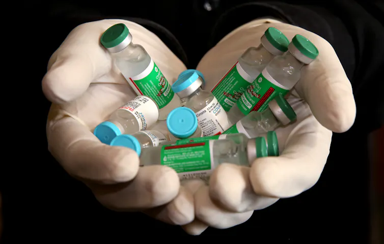 A person holding vials of the Covishield and Covaxin vaccines.