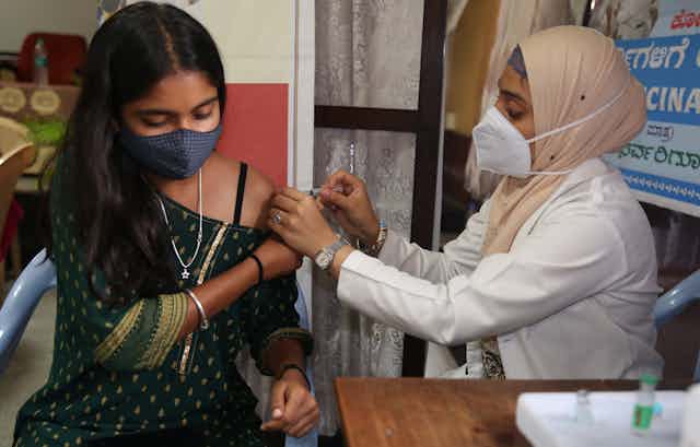 An Indian woman being vaccinated by a health worker