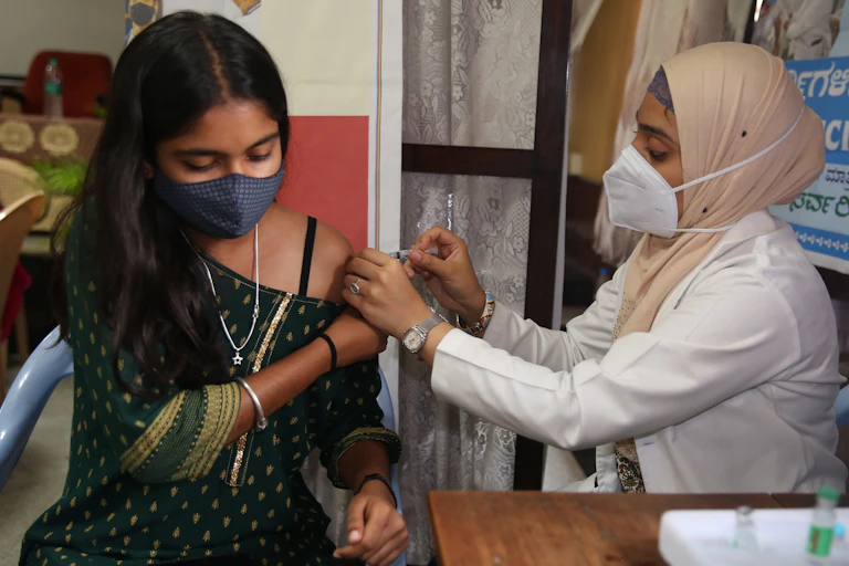 An Indian woman being vaccinated by a health worker