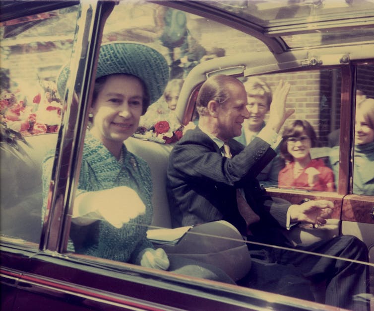 Queen Elizabeth and Prince Phillip ride in the back of a car