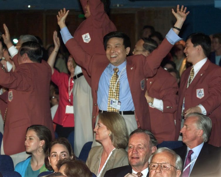 People in red coats stand cheering