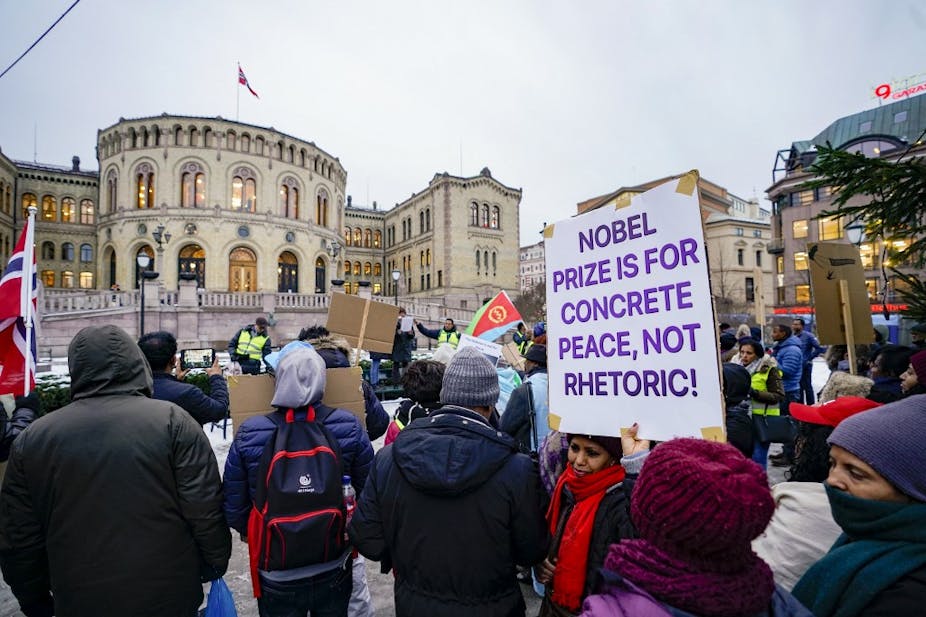 Manifestants devant le Parlement norvégien avec une pancarte où il est écrit en anglais : "Le prix Nobel est un prix pour la paix, pas pour la rhétorique !"
