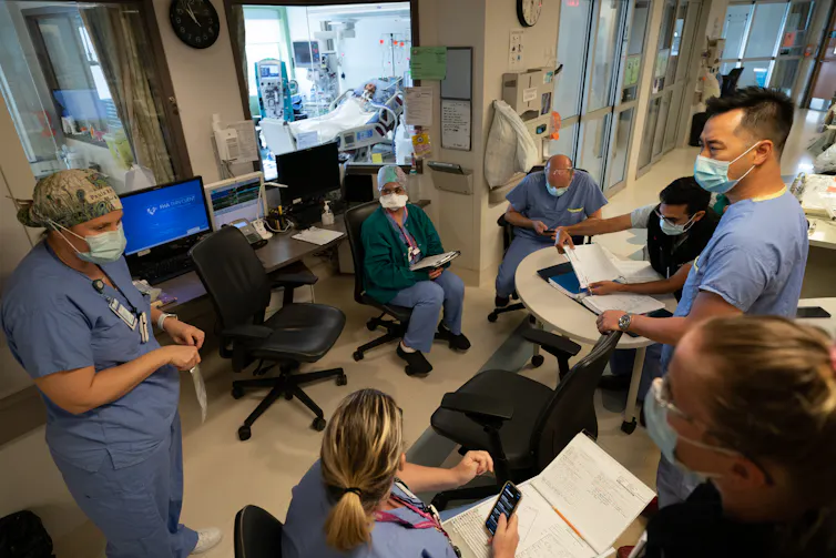 Doctors and nurses gather in a room at a hospital during the COVID-19 pandemic.