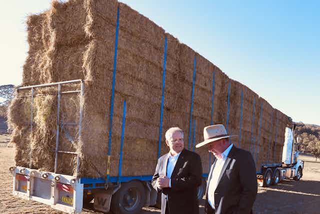 two men in front of hay truck