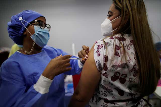 Health worker giving woman her third Pfizer dose, in Panama
