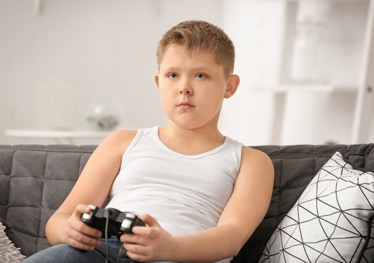 Boy sitting on couch as he operates a game controller