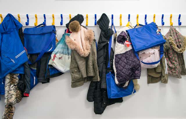 Primary school pupils' bags and coats hang from pegs