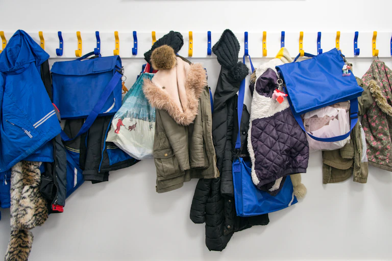 Primary school pupils' bags and coats hang from pegs