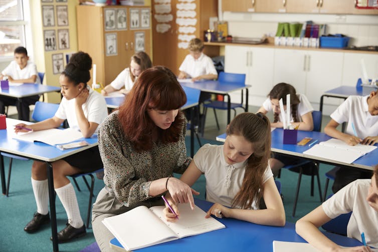 A teacher sits with a pupil in class